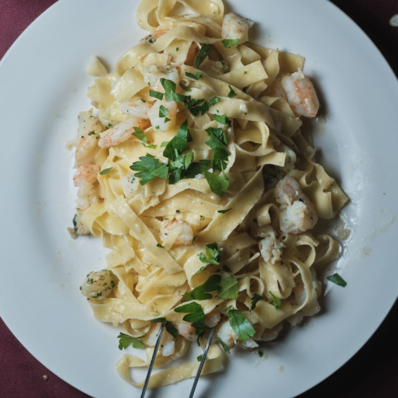 A plate of paste with shrimp in a light sauce